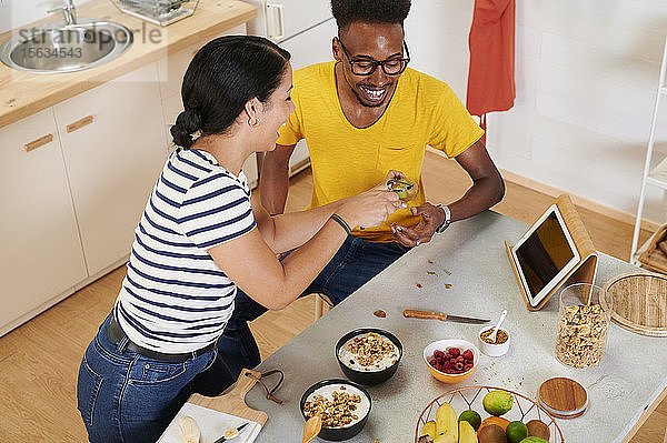 Multiethnisches Paar frühstückt gemeinsam in der Küche  Talbet im Halter