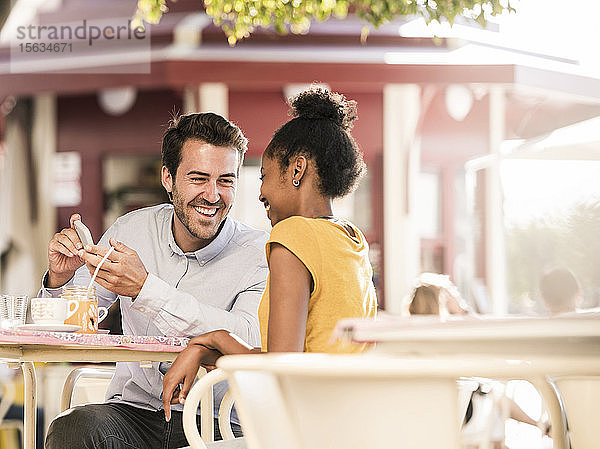 Glückliches junges Paar mit Handy in einem Café im Freien