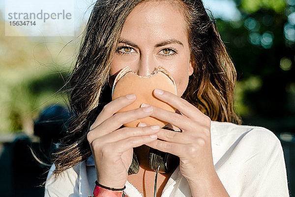 Junge Frau  die ihr Gesicht mit einem Hamburger bedeckt