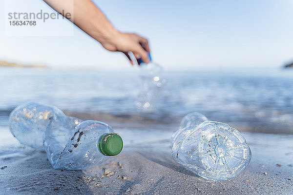 Handsammlung leerer Plastikflaschen am Meeresufer