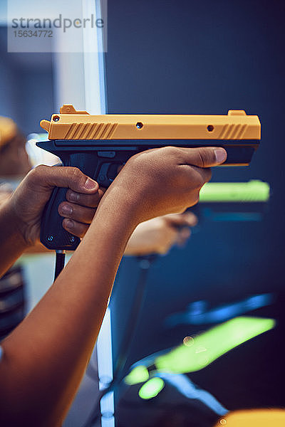 Hand eines Teenagers  der in einer Spielhalle mit einer Pistole schießt