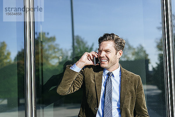 Glücklicher Geschäftsmann am Telefon im städtischen Geschäftsviertel  Madrid  Spanien