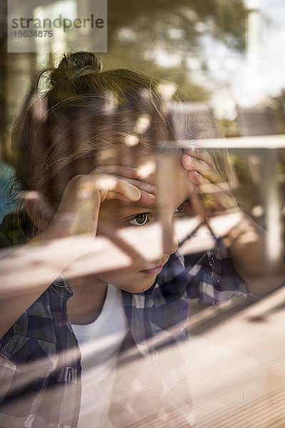 Porträt eines Mädchens  das durch ein Fenster schaut