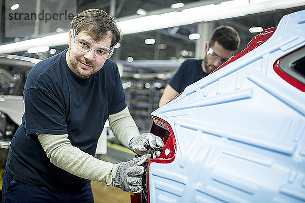 Porträt eines selbstbewussten Mannes  der in einer modernen Autofabrik arbeitet