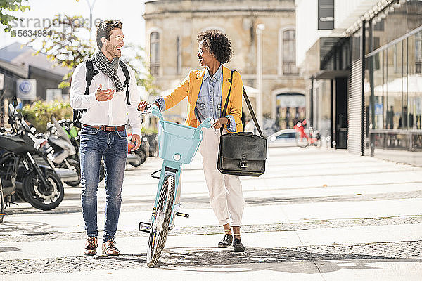 Glücklicher junger Mann und Frau mit Fahrrad in der Stadt unterwegs