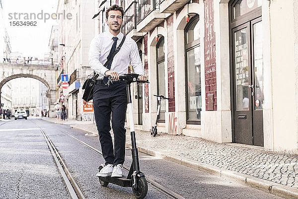Junger Geschäftsmann fährt E-Scooter in der Stadt  Lissabon  Portugal