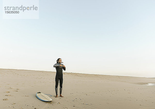 Portugal  Costa Nova  Surfer ziehen am Strand stehend Neopren an