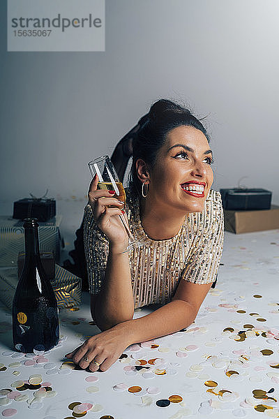 Porträt einer jungen Frau  die für eine Party gekleidet ist und Weihnachten mit Geschenken und Champagner feiert