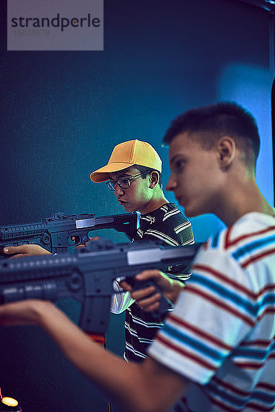 Teenager-Freunde schießen mit Gewehren in einer Spielhalle