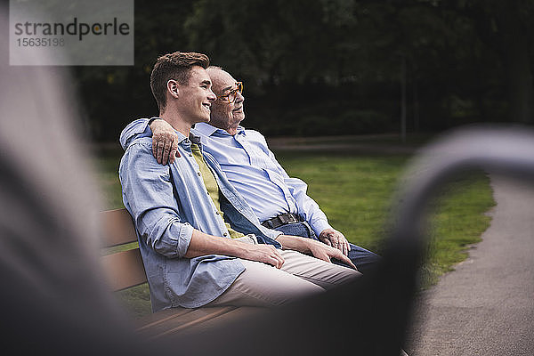 Älterer Mann und Enkel entspannen sich gemeinsam auf einer Parkbank