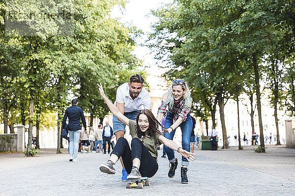 Gruppe von drei Freunden amüsiert sich mit Skateboard