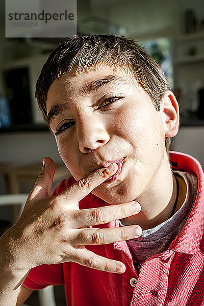 Porträt eines Jungen zu Hause  der sich den Finger leckt