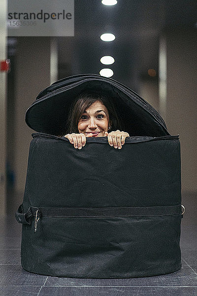 Lächelnde Frau versteckt sich in einer großen Tasche für Trommeln
