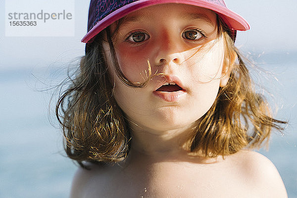 Porträt eines kleinen Mädchens mit Mütze am Strand
