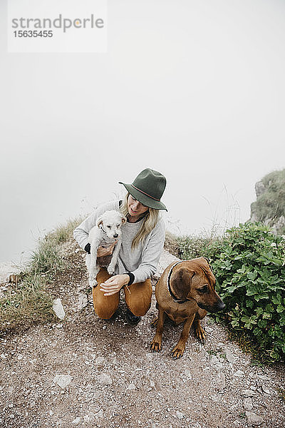 Junge Frau mit zwei Hunden auf dem Aussichtspunkt