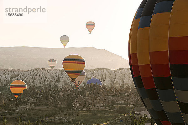 Bunte Heißluftballons fliegen bei Sonnenuntergang über die Berge im Goreme-Nationalpark  Kappadokien  Türkei