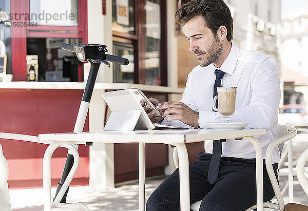 Junger Geschäftsmann mit Tablet und Mobiltelefon in einem Café in der Stadt  Lissabon  Portugal