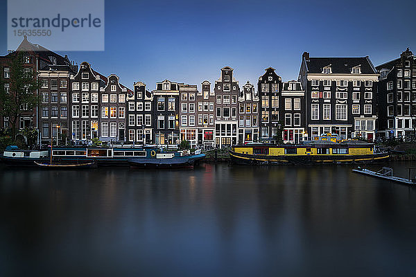 Niederlande  Amsterdam  Verschiedene Boote liegen entlang des Stadtkanals mit Häuserzeilen im Hintergrund