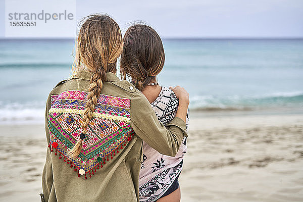 Rückansicht von zwei jungen Frauen  die nahe beieinander an einem Strand stehen