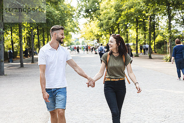 Glückliches junges Paar geht Hand in Hand in einem Park