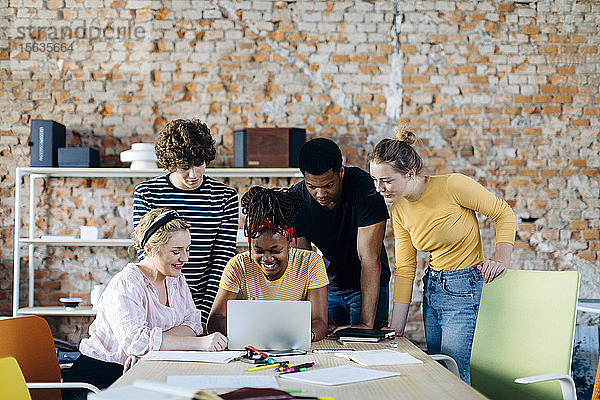 Junge Menschen arbeiten gemeinsam am Tisch mit Laptop