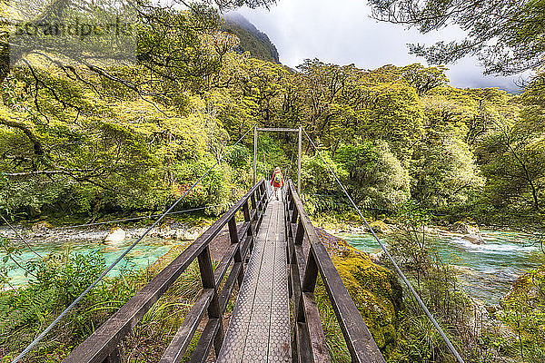 Wanderin beim Überqueren der Drehbrücke über den Fluss  Fiordland National Park  Südinsel  Neuseeland