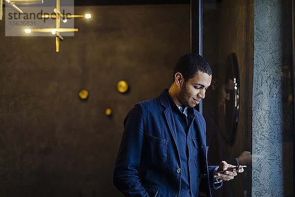 Junger Mann in stilvollem Büro  mit Smartphone