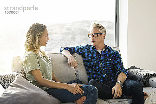 Paar im Gespräch auf der Couch in einem modernen Zuhause