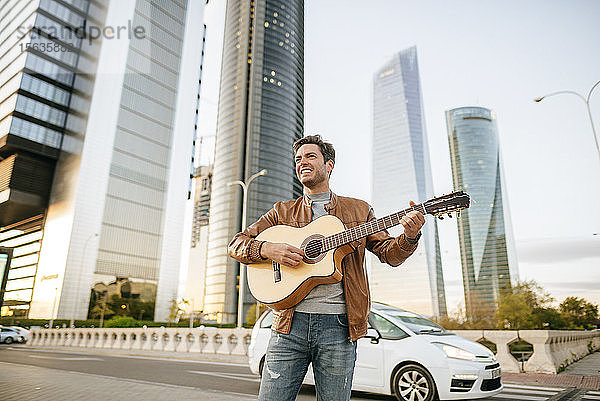 Lächelnder Mann spielt Gitarre in der Stadt  Madrid  Spanien