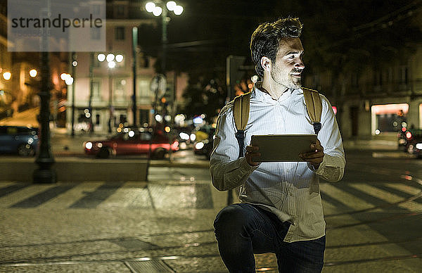 Porträt eines jungen Mannes mit Handy und Kopfhörer in der Stadt bei Nacht  Lissabon  Portugal