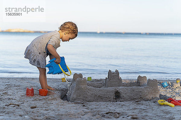 Süßes Kleinkind baut eine Sandburg am Strand
