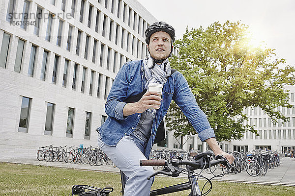 Student mit Kaffee zum Mitnehmen und E-Bike