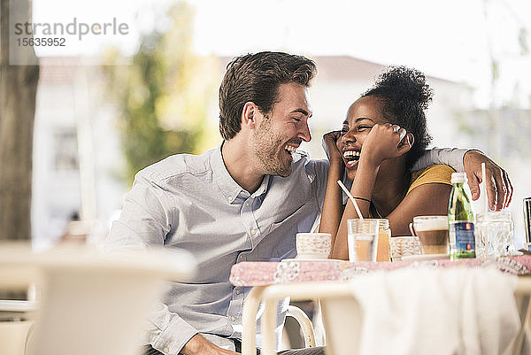 Lachendes junges Paar in einem Straßencafé