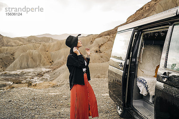 Junge Frau in Wüstenlandschaft neben einem Wohnmobil stehend  Almeria  Andalusien  Spanien