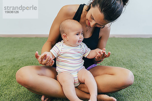 Junge Mutter und Baby beim Mutter-Kind-Turnen trainieren