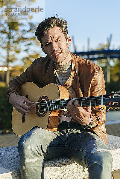 Porträt eines Mannes  der im Freien Gitarre spielt