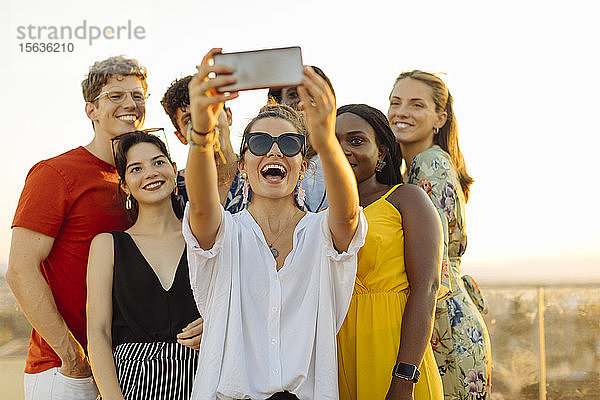 Gruppe glücklicher multiethnischer Freunde  die sich während einer Party am Abend ein Selfie gönnt