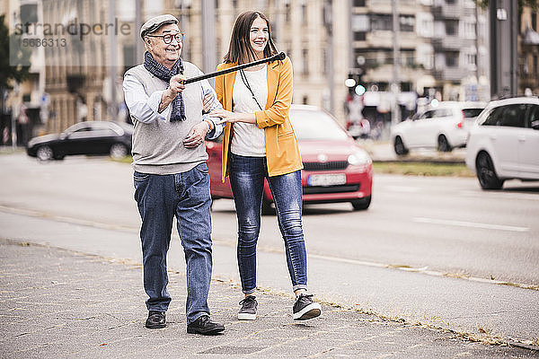 Erwachsene Enkelin  die ihrem Großvater beim Laufen hilft