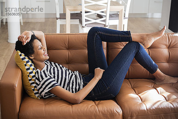 Entspannte junge Frau liegt zu Hause auf der Couch