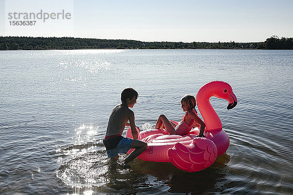 Bruder und Schwester mit Flamingo-Pool schwimmen auf dem See