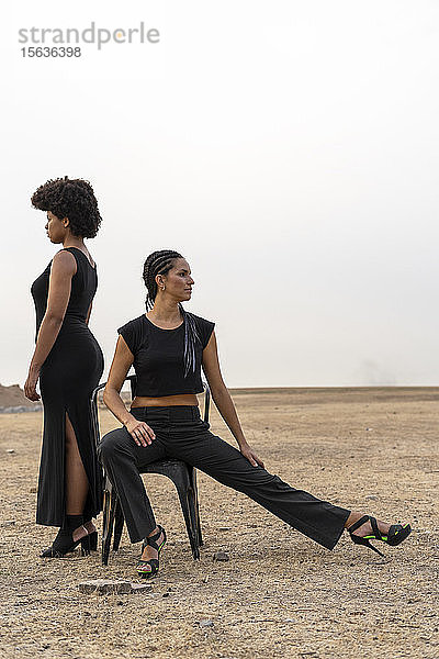 Zwei schwarz gekleidete Frauen in trostloser Landschaft