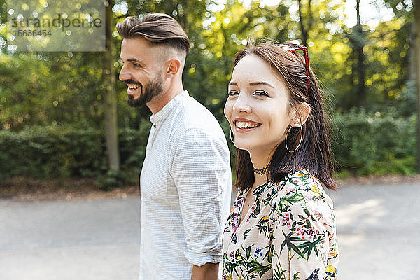 Porträt eines glücklichen jungen Paares beim Spaziergang in einem Park