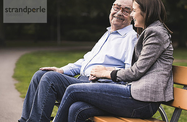 Älterer Mann und Enkelin entspannen gemeinsam auf einer Parkbank