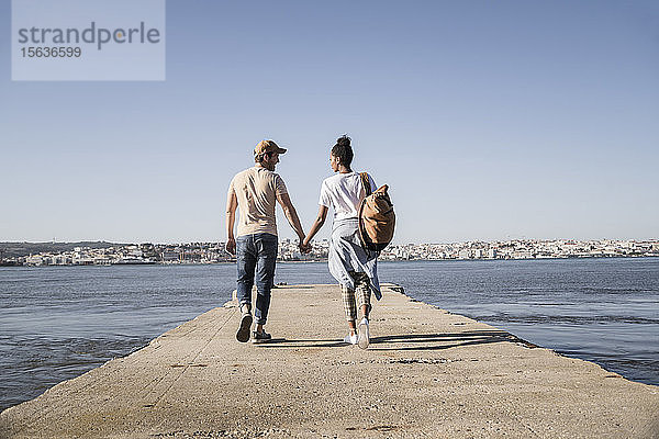 Junges Paar beim Spaziergang am Pier am Wasser  Lissabon  Portugal