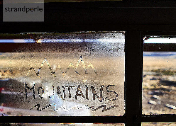 Das Wort Berge auf einer gedämpften Fensterscheibe geschrieben
