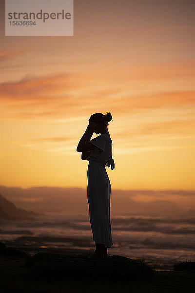 Junge blonde Frau im Badeanzug bei Sonnenaufgang am Strand