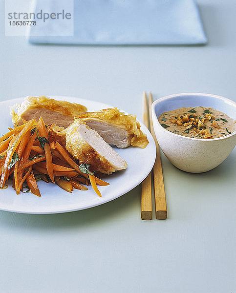 Nahaufnahme von Hühnerbrust mit Karotten und Erdnusssauce auf dem Tisch