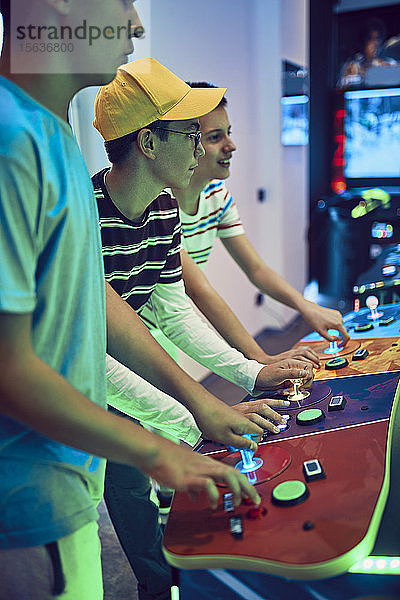 Teenager-Freunde spielen mit einem Spielautomaten in einer Spielhalle