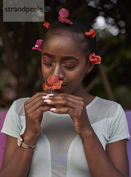 Porträt einer jungen Frau  die an einer Blume riecht