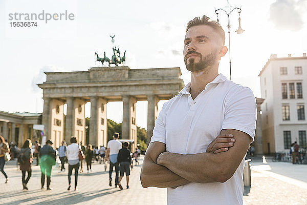 Porträt eines jungen Mannes  der vor dem Brandenburger Tor im Gegenlicht steht  Berlin  Deutschland